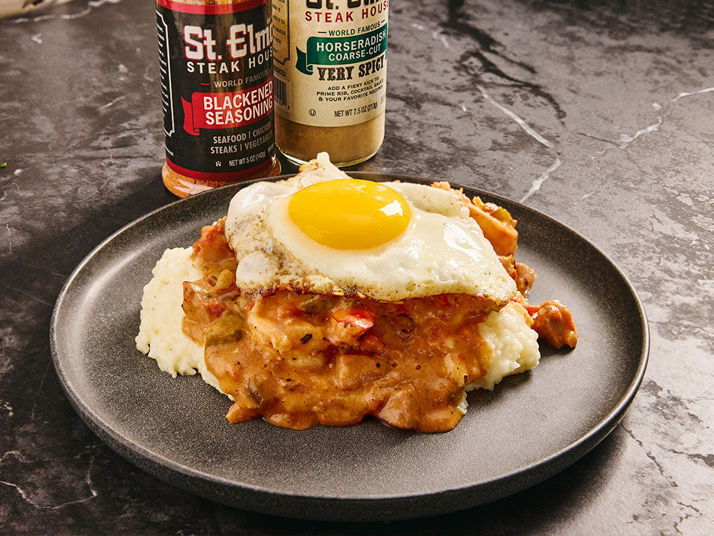 Shrimp and grits with gouda cheese, blackened shrimp, creamy sauce, and a fried egg, served on a black plate.