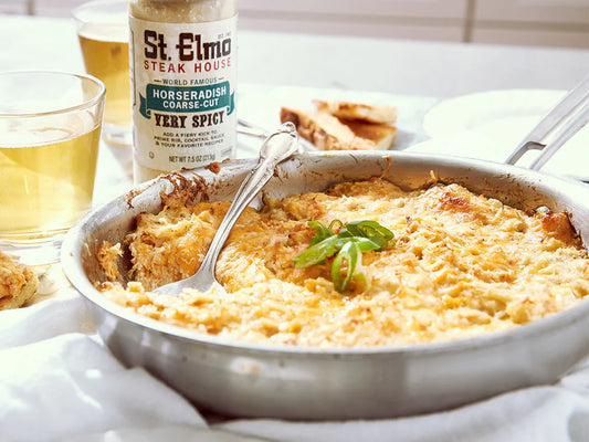 Warm creamy crab dip baked with melted cheddar and parmesan cheese, garnished with green onions and served in a skillet.